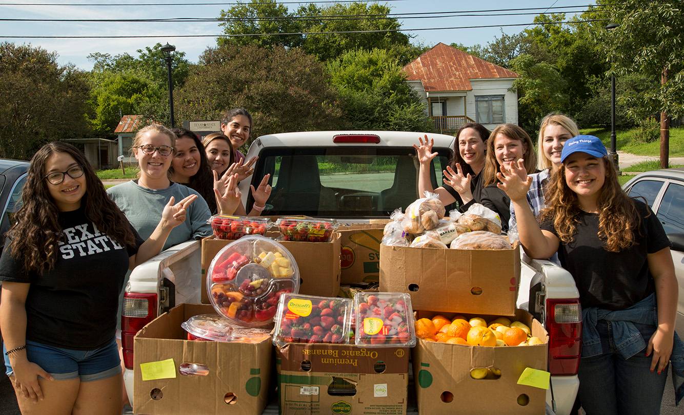 students standing near truck bed filled with food