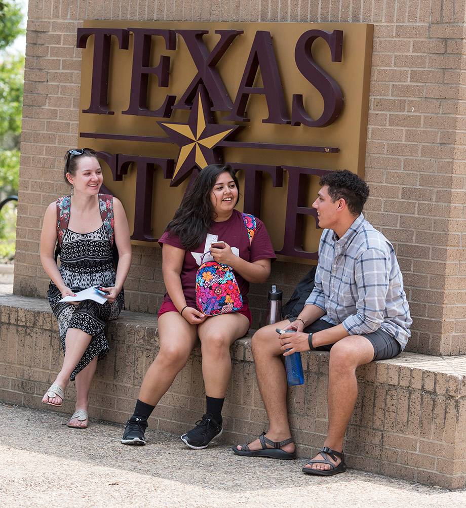 three students talking near texas state sign
