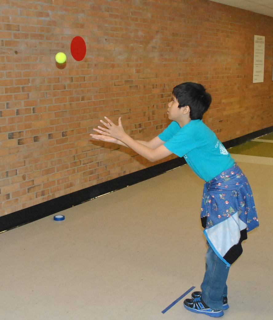 boy tossing a ball at a wall