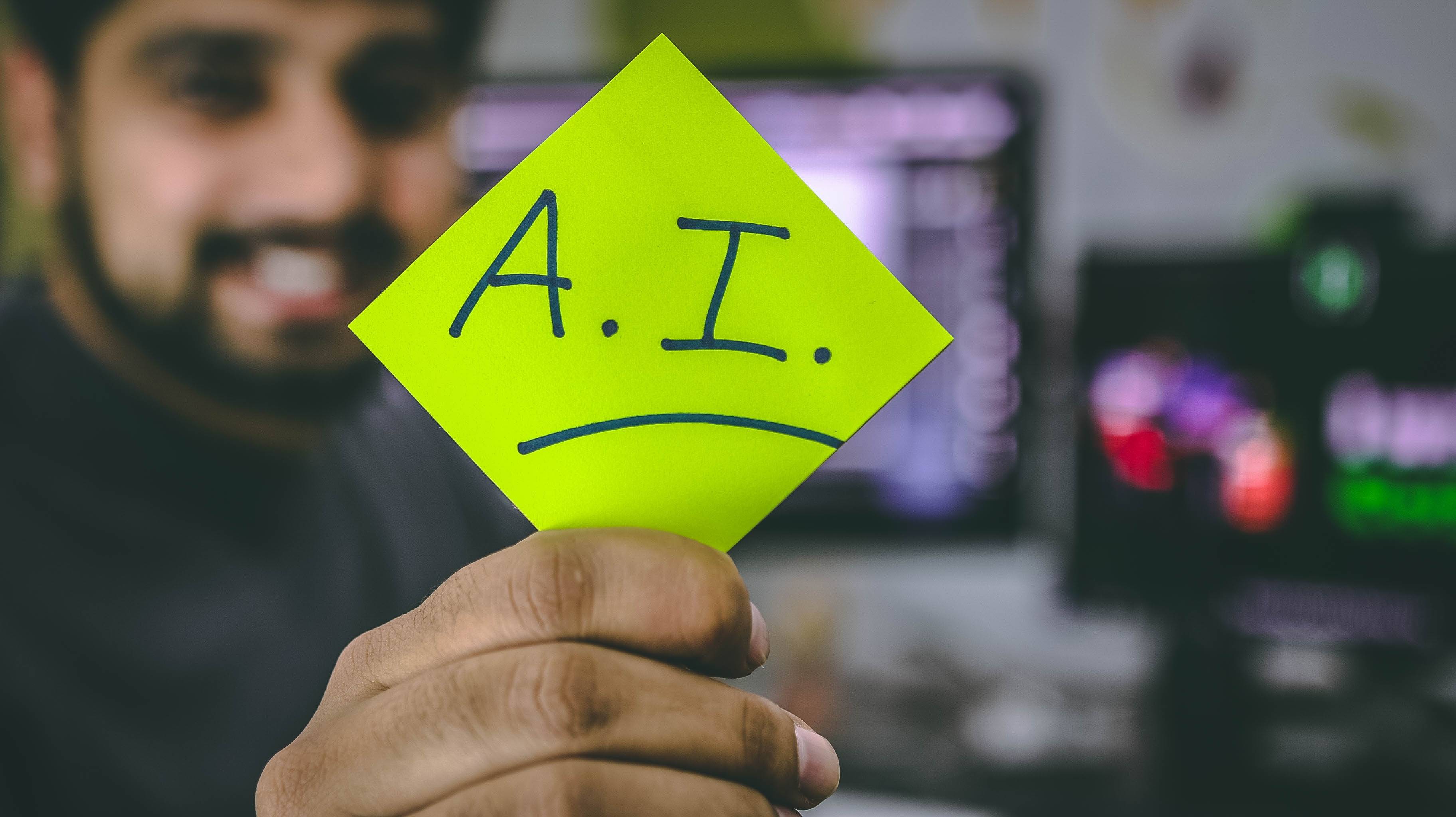 Man holding a post it note that says "A.I"