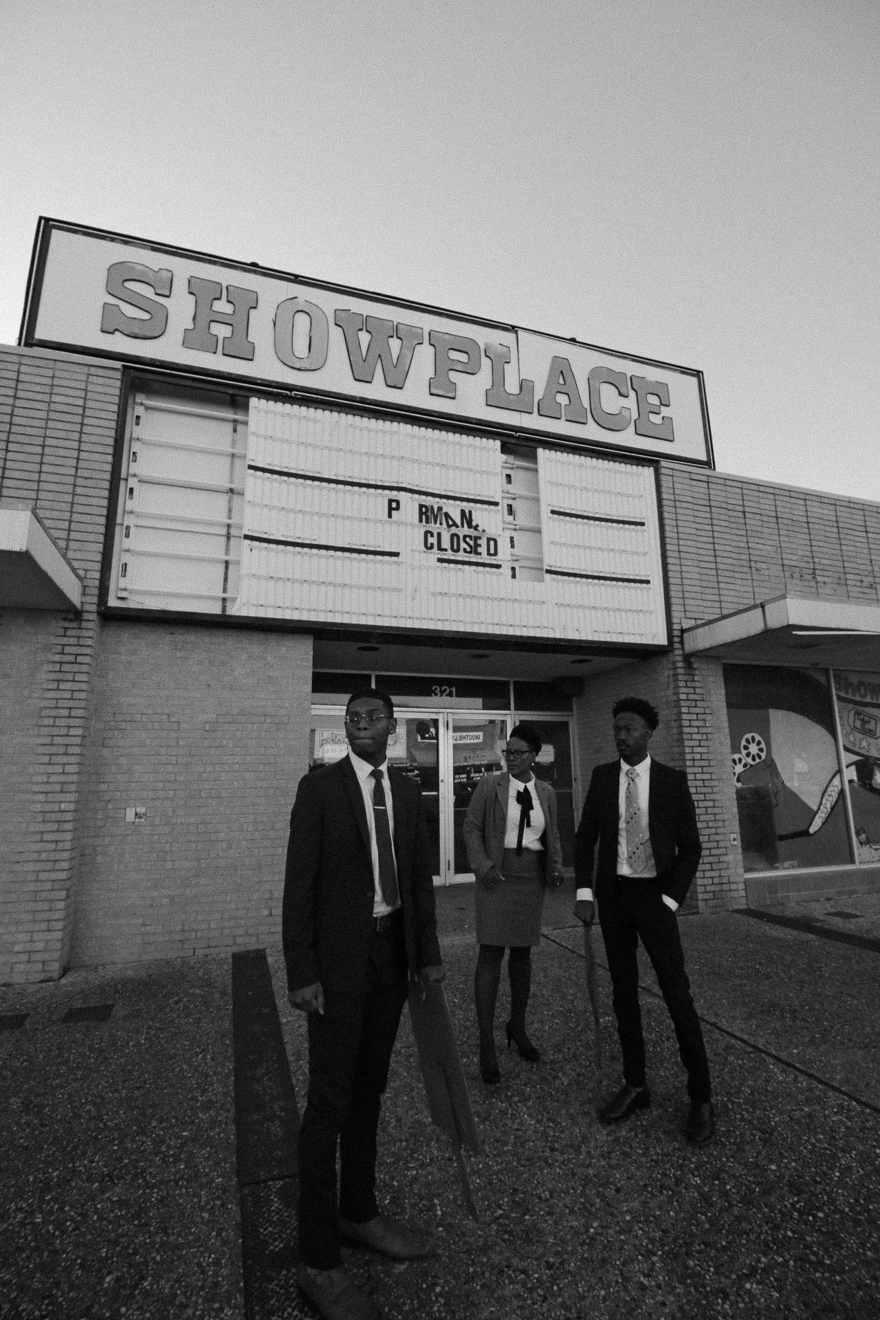three people standing in front of old theatre