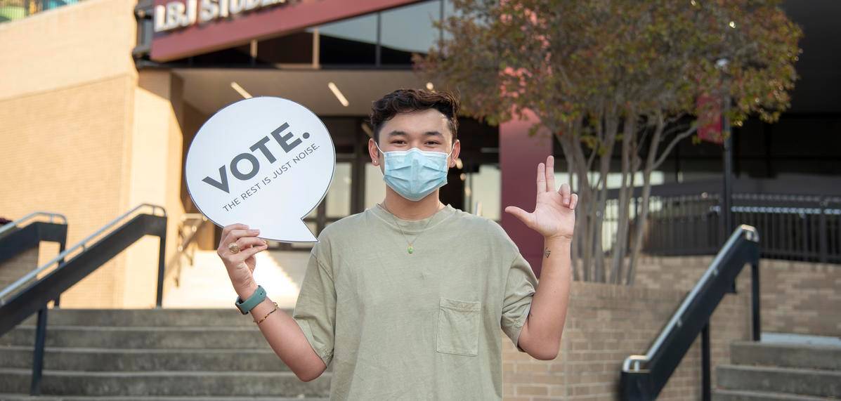 student holding sign reading "VOTE."