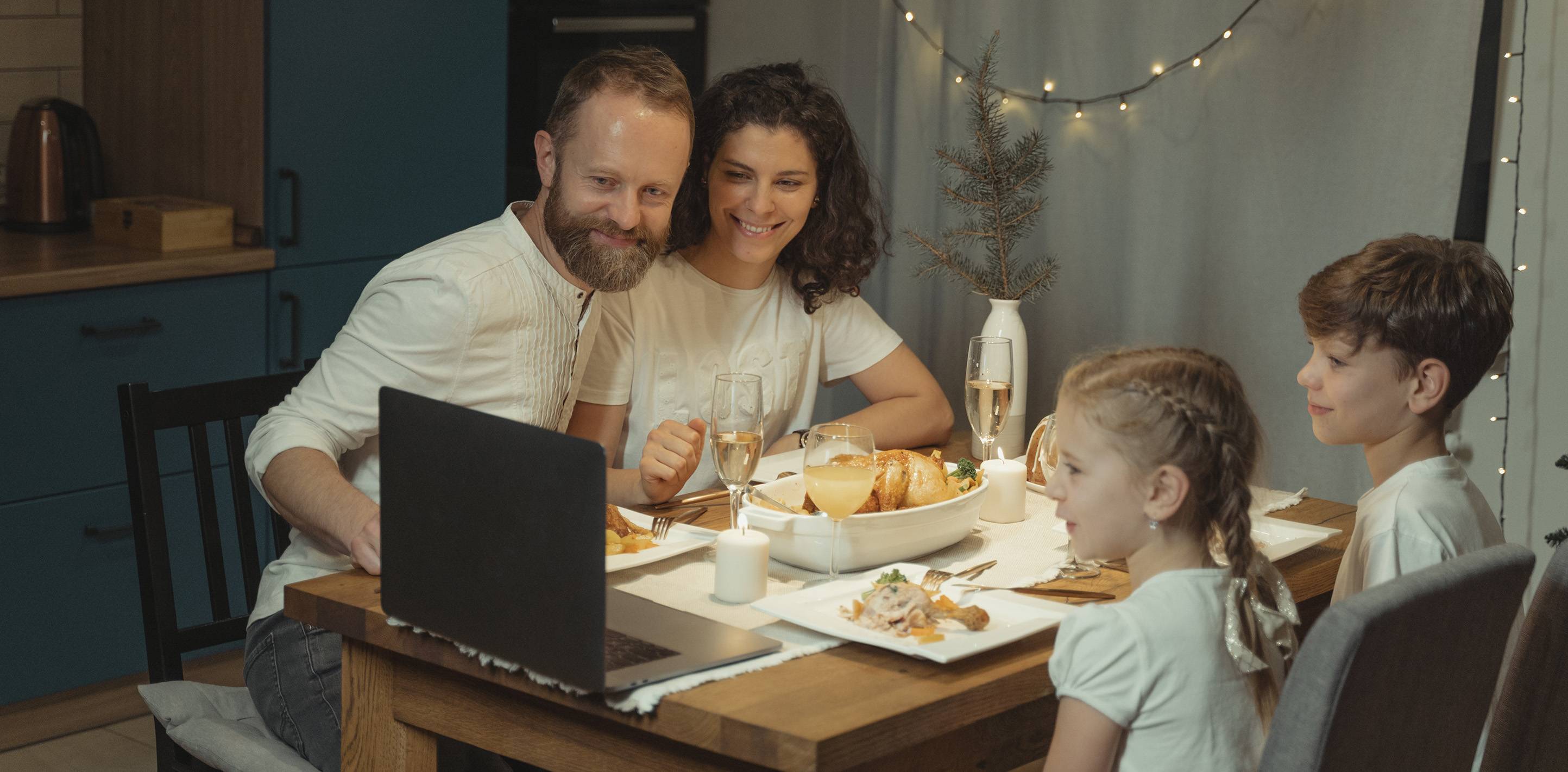 family at dinner table looking at computer