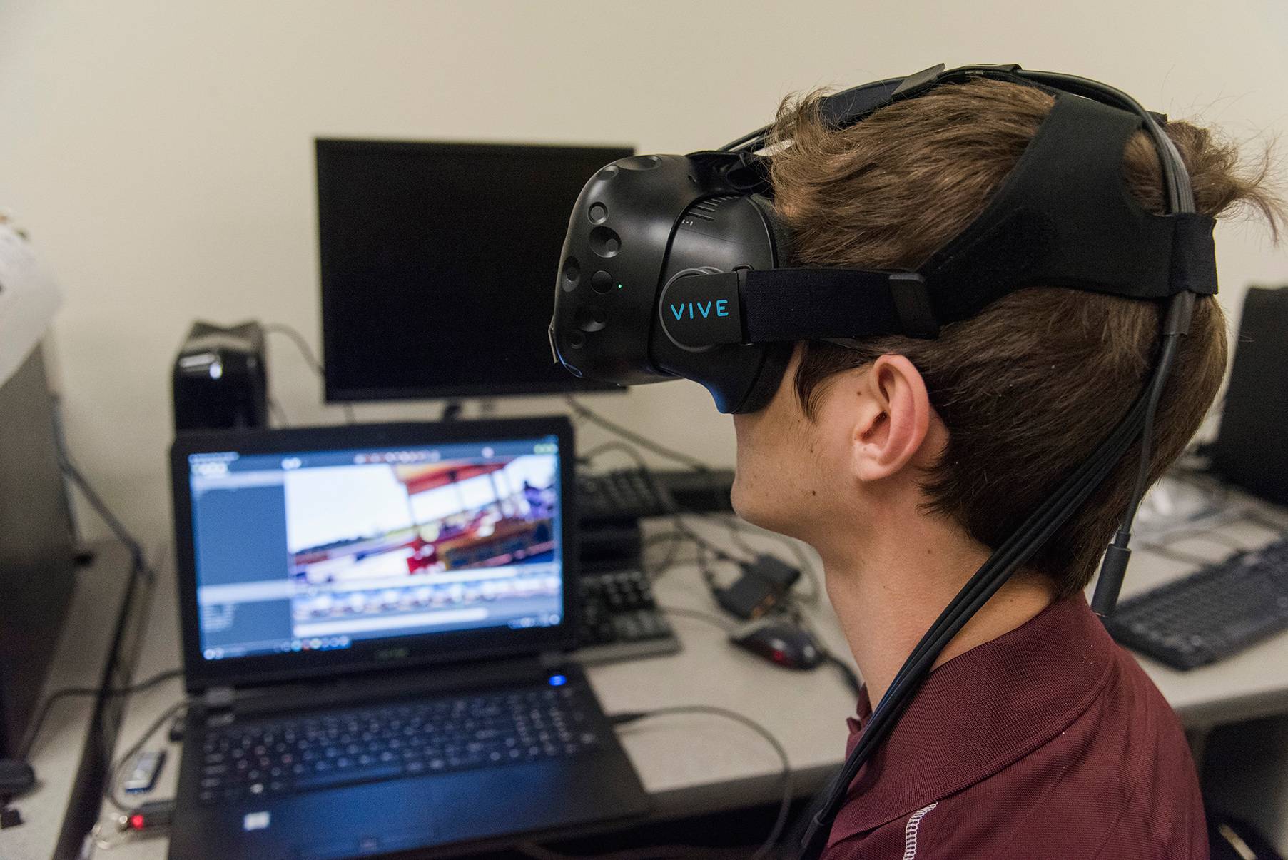 young man wearing VR headset next to laptop