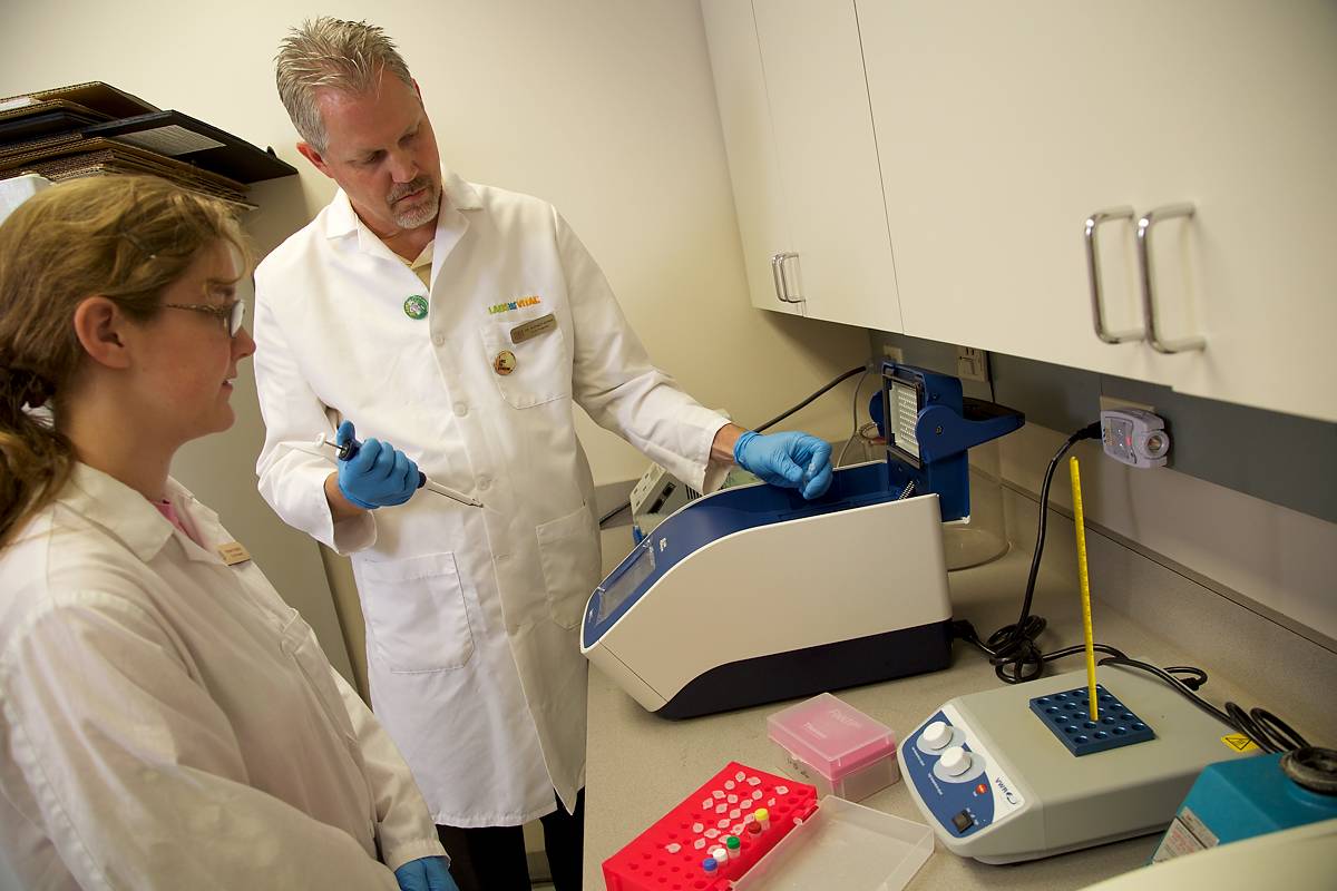 female student and male faculty member working on laboratory equipment