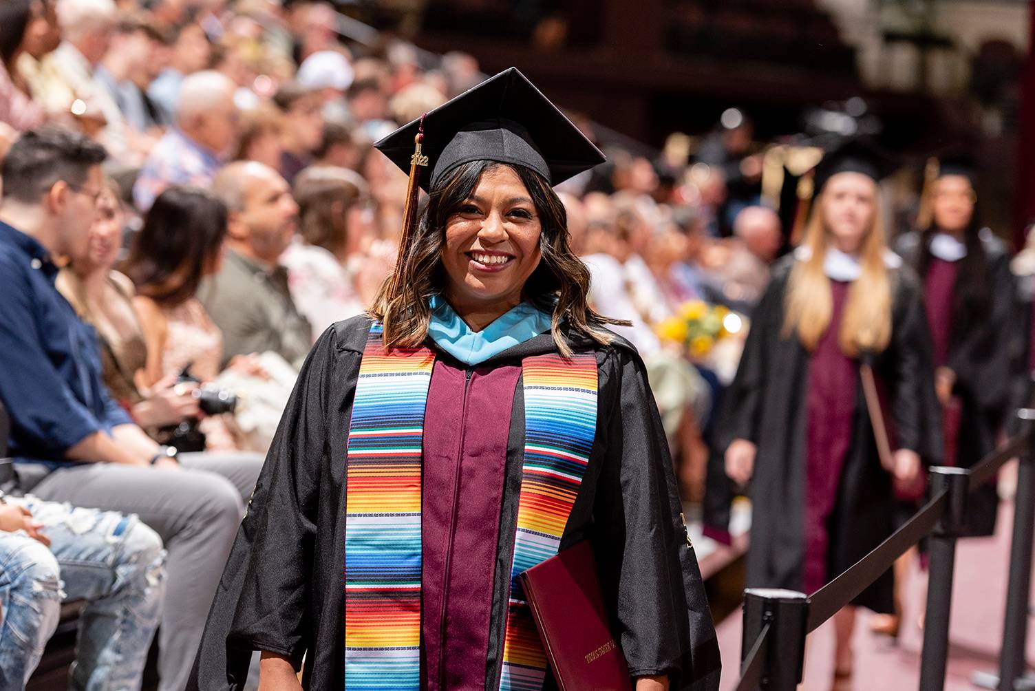 hispanic woman in graduation cap and gown