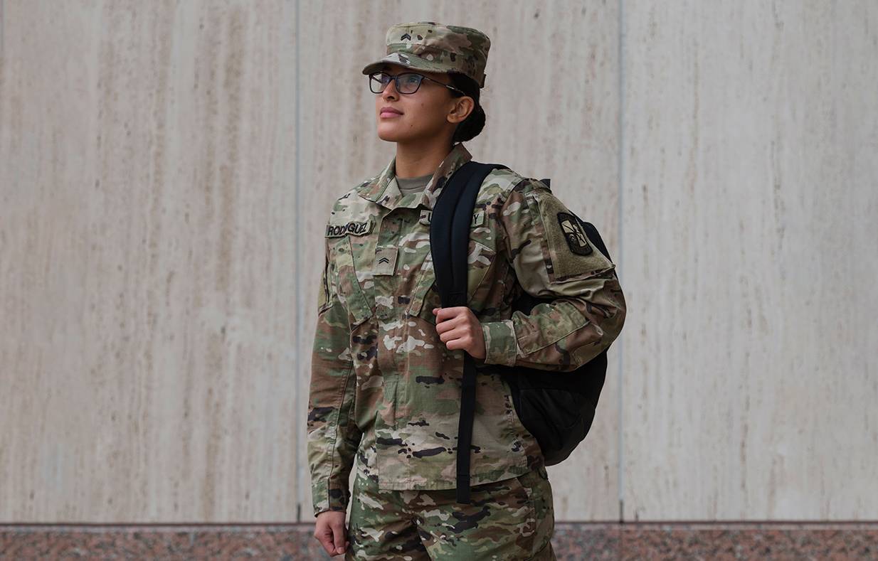 female in military uniform holding backpack