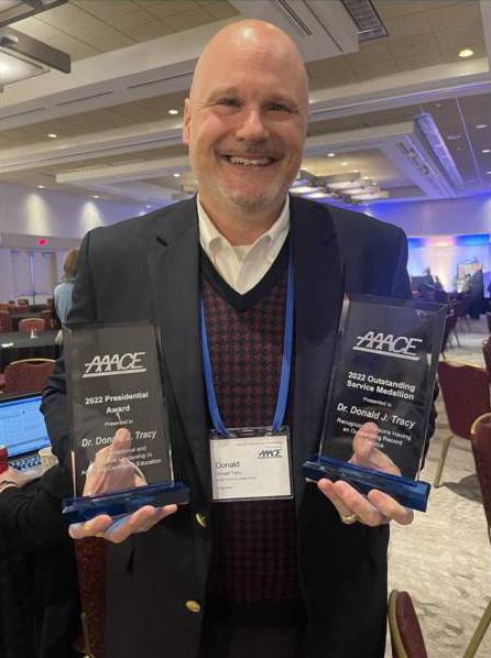 man holding two awards