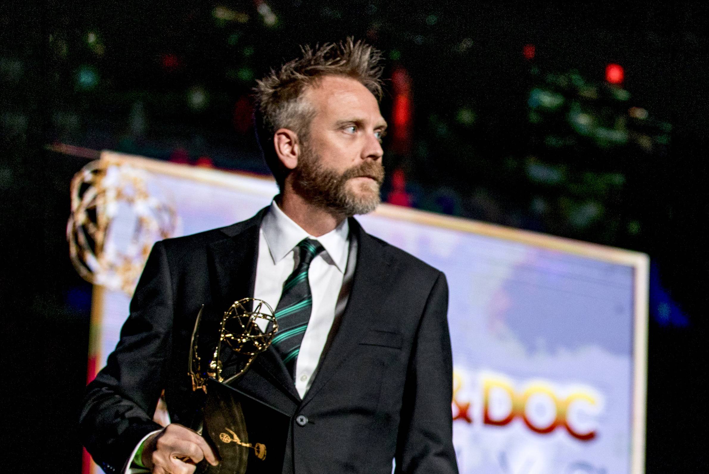 MAN HOLDING EMMY AWARD WHILE ON STAGE