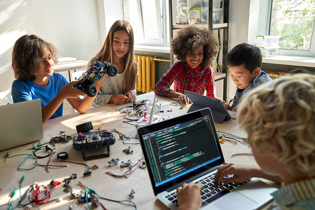 kids learning programming robot vehicles sitting at table at STEM education science engineering