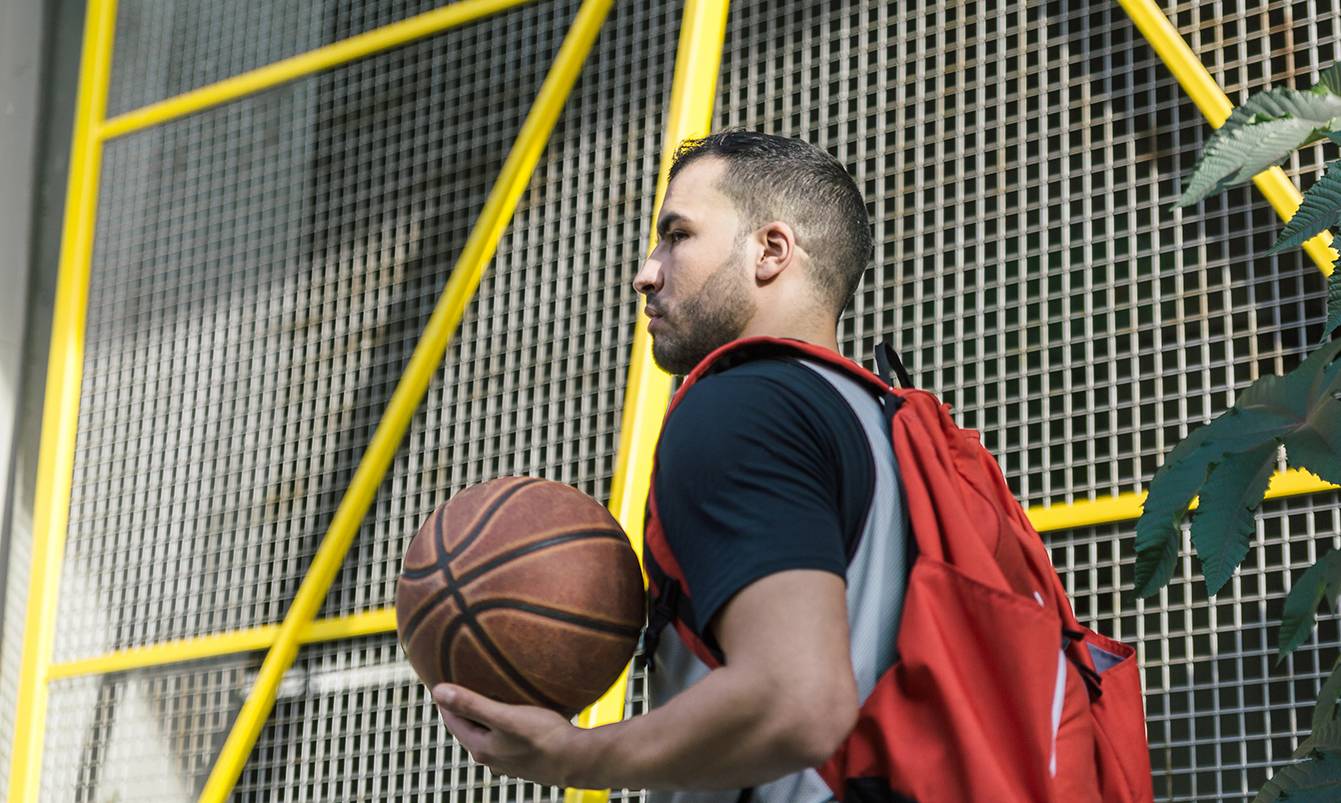 man carrying basketball and wearing backpack