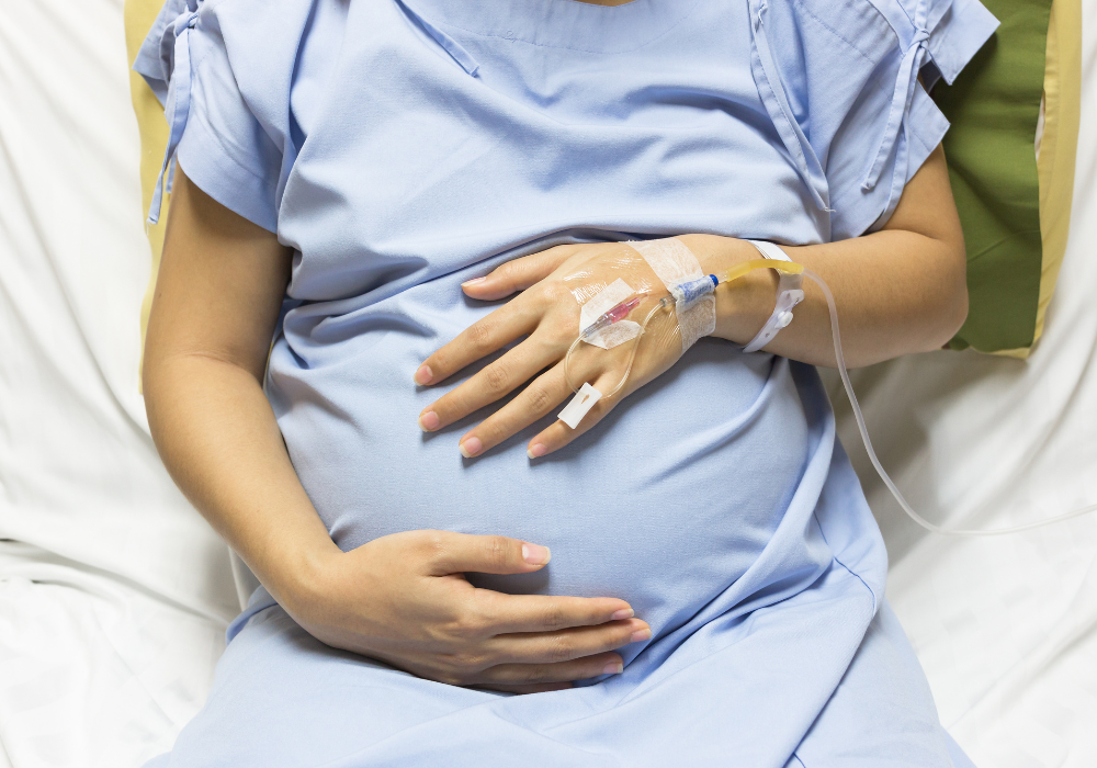 pregnant woman holding her stomach in a hospital bed