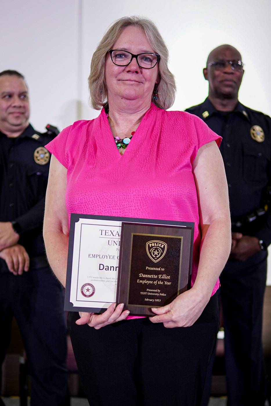 woman in pink shirt smiling with awards