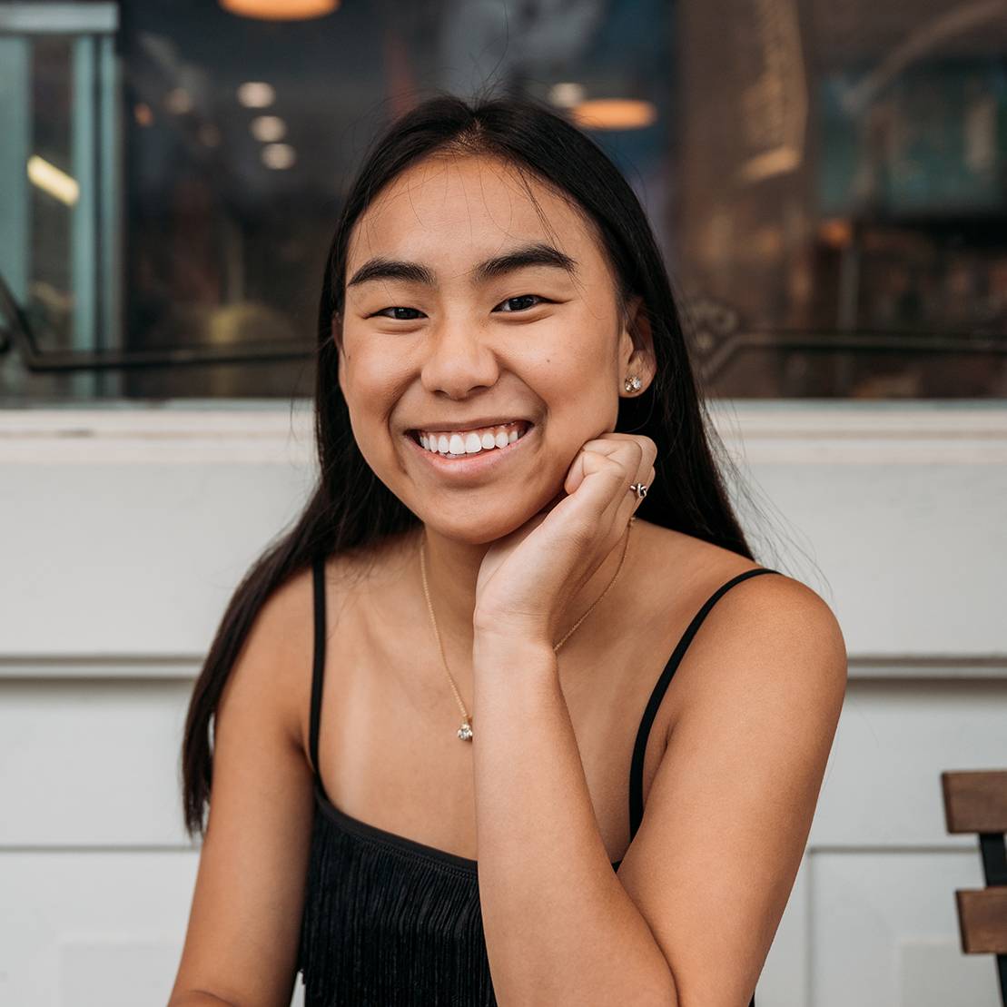 female student smiling with hand on chin