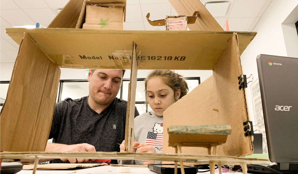 man and child building tower with cardboard box
