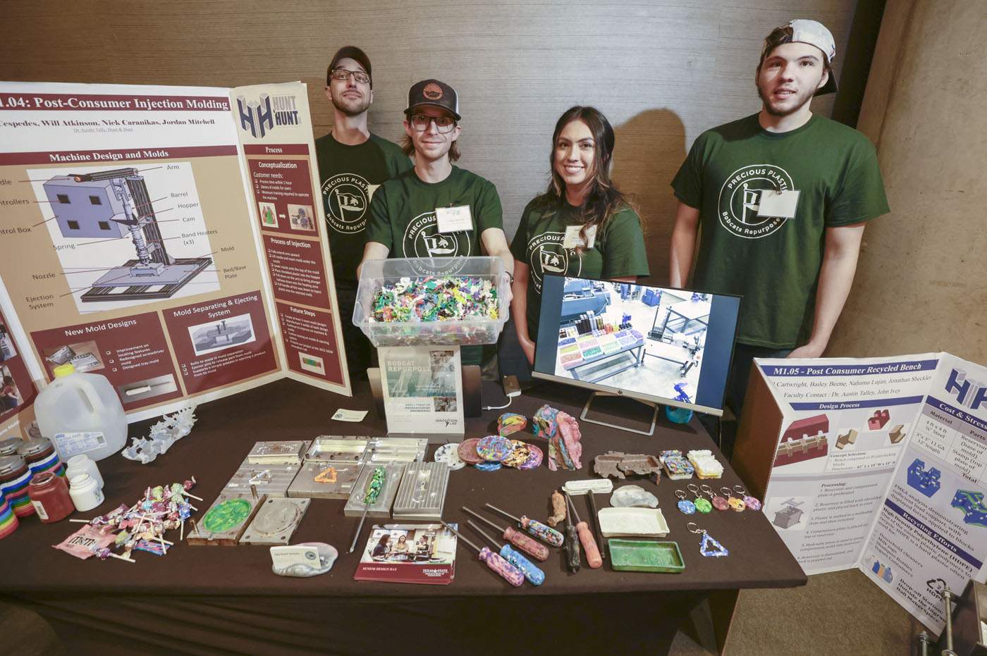 four students standing behind table displaying research