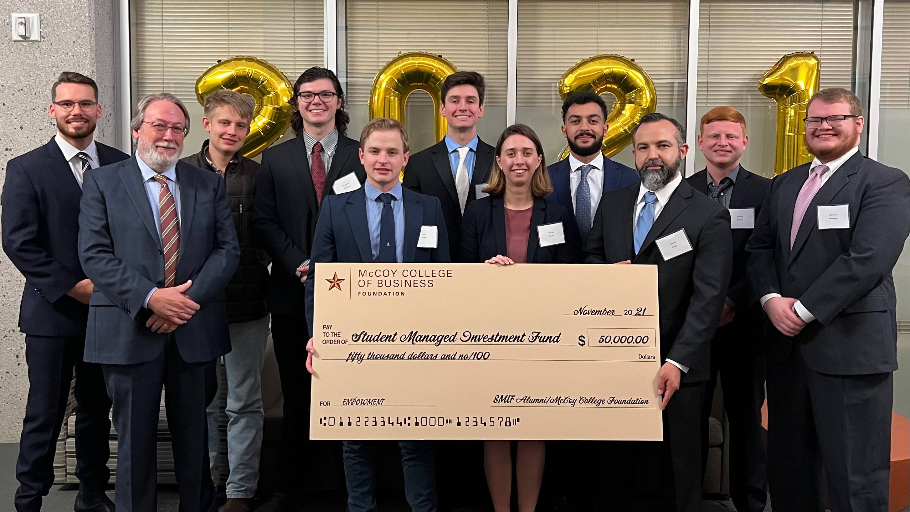 large group of people in suits holding large check