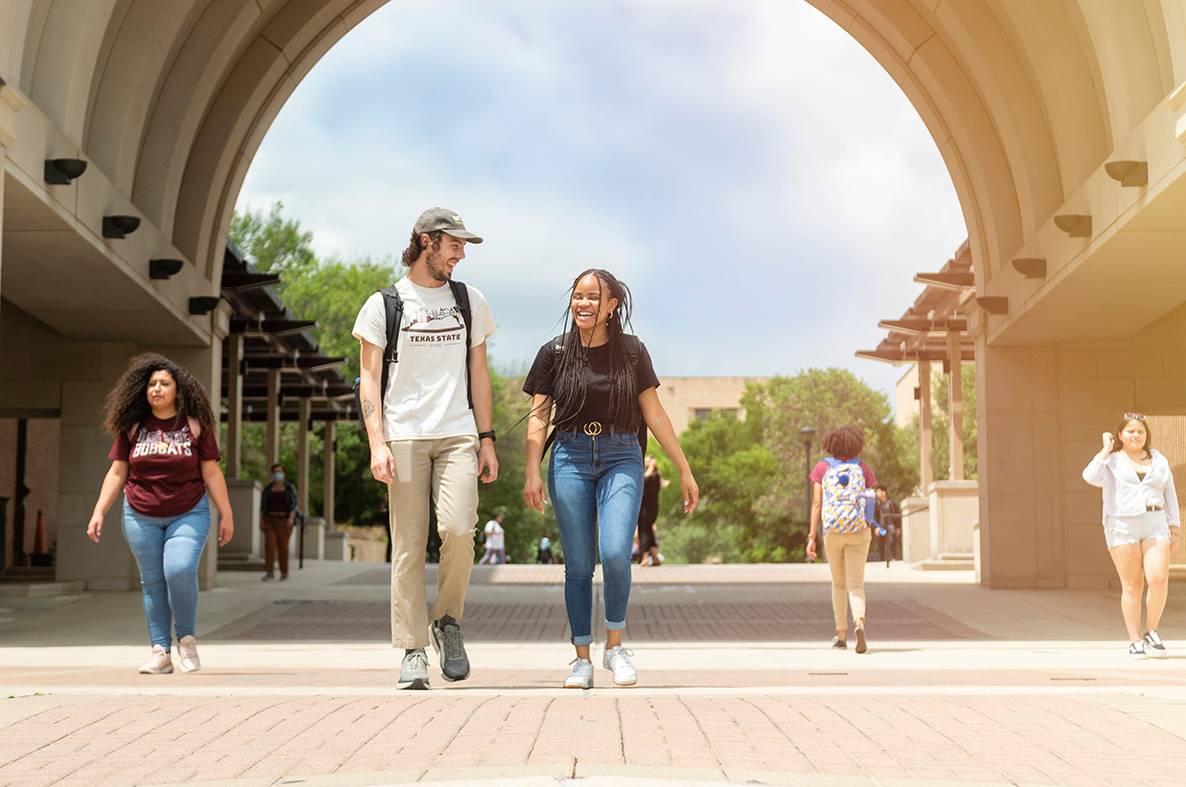 students walking on campus through arch