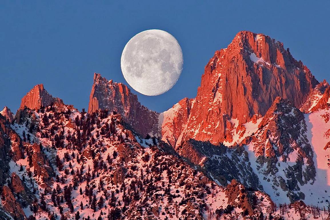 photo of moon behind mountain ridge