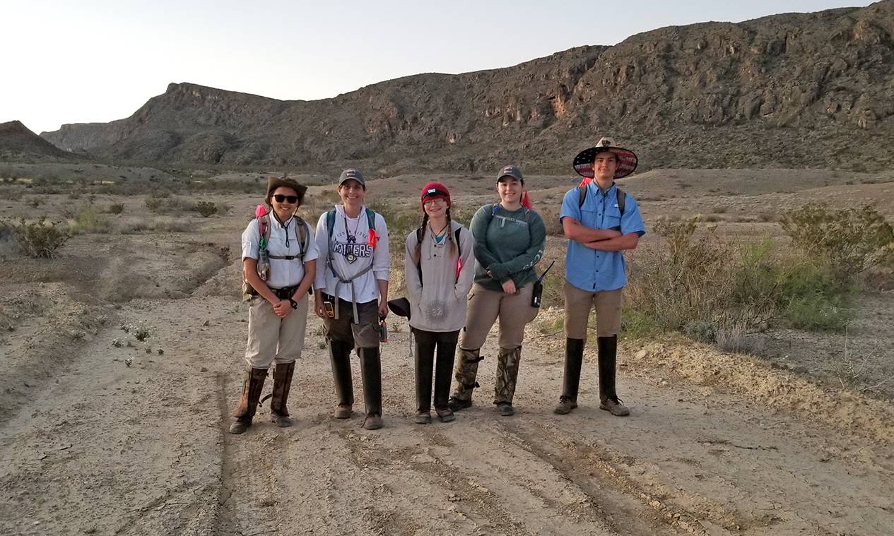 five students standing in front of large rock formation in Big Bend National Park