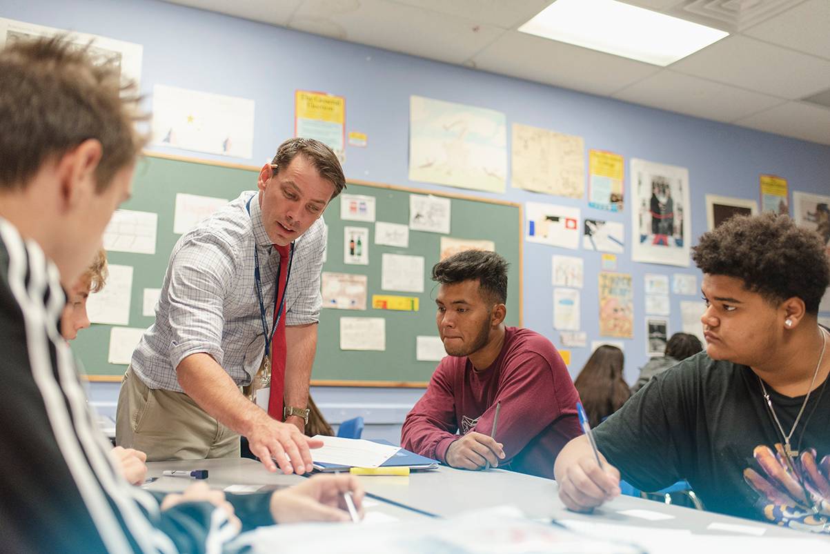 male teacher helping three male students