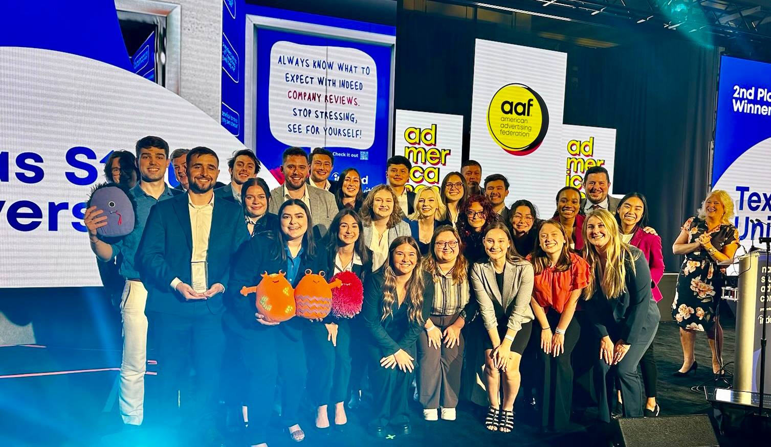 large group of students pose for a photo on stage at award ceremony