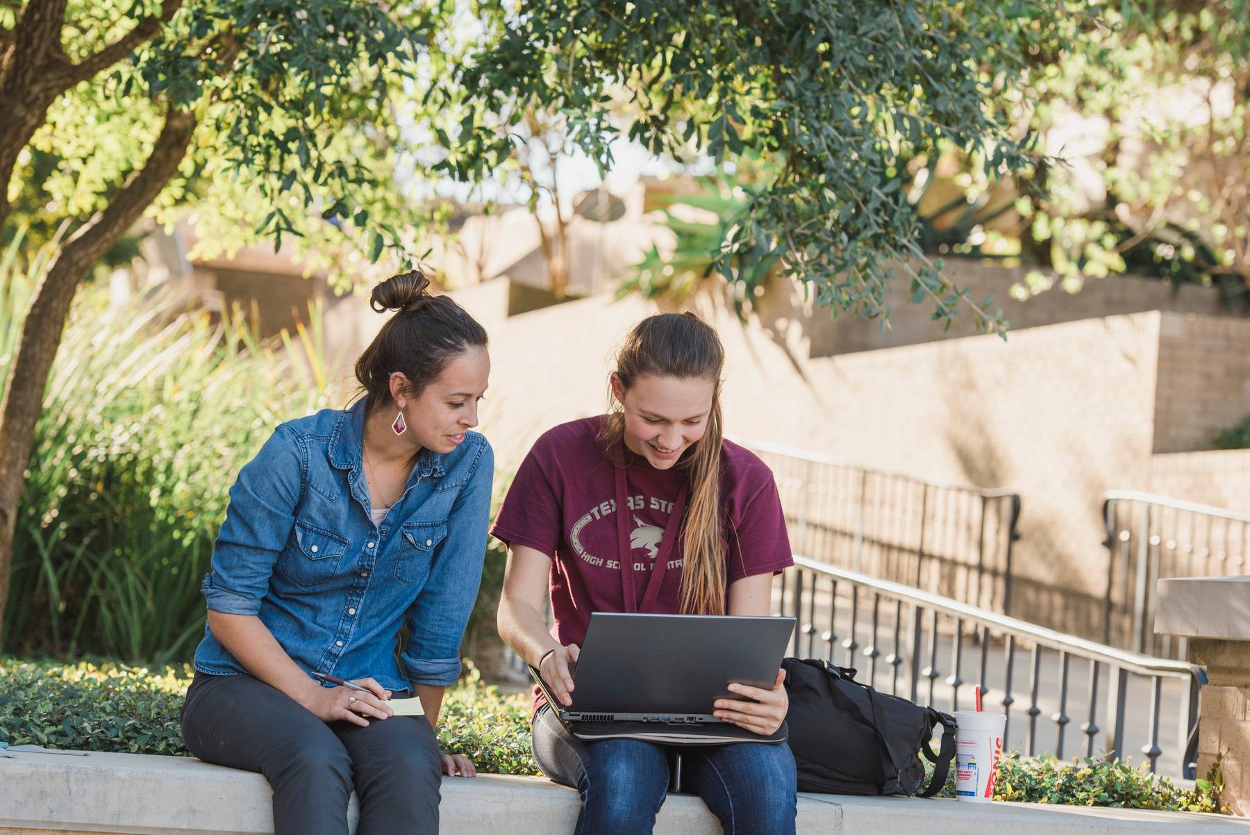 photo of students looking at laptop outside