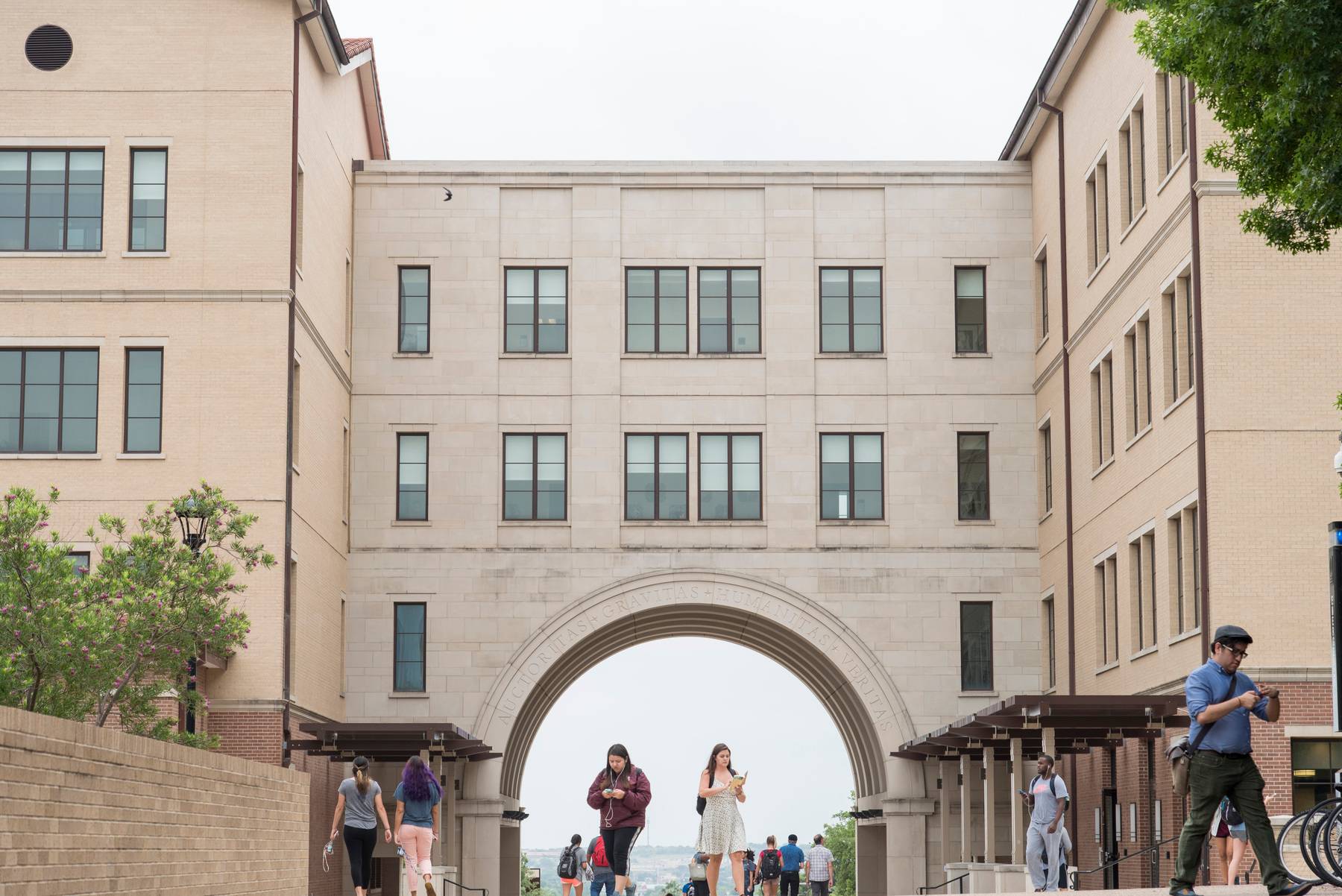 Exterior of Texas State Undergraduate Admission Center with students walking beneath the arch