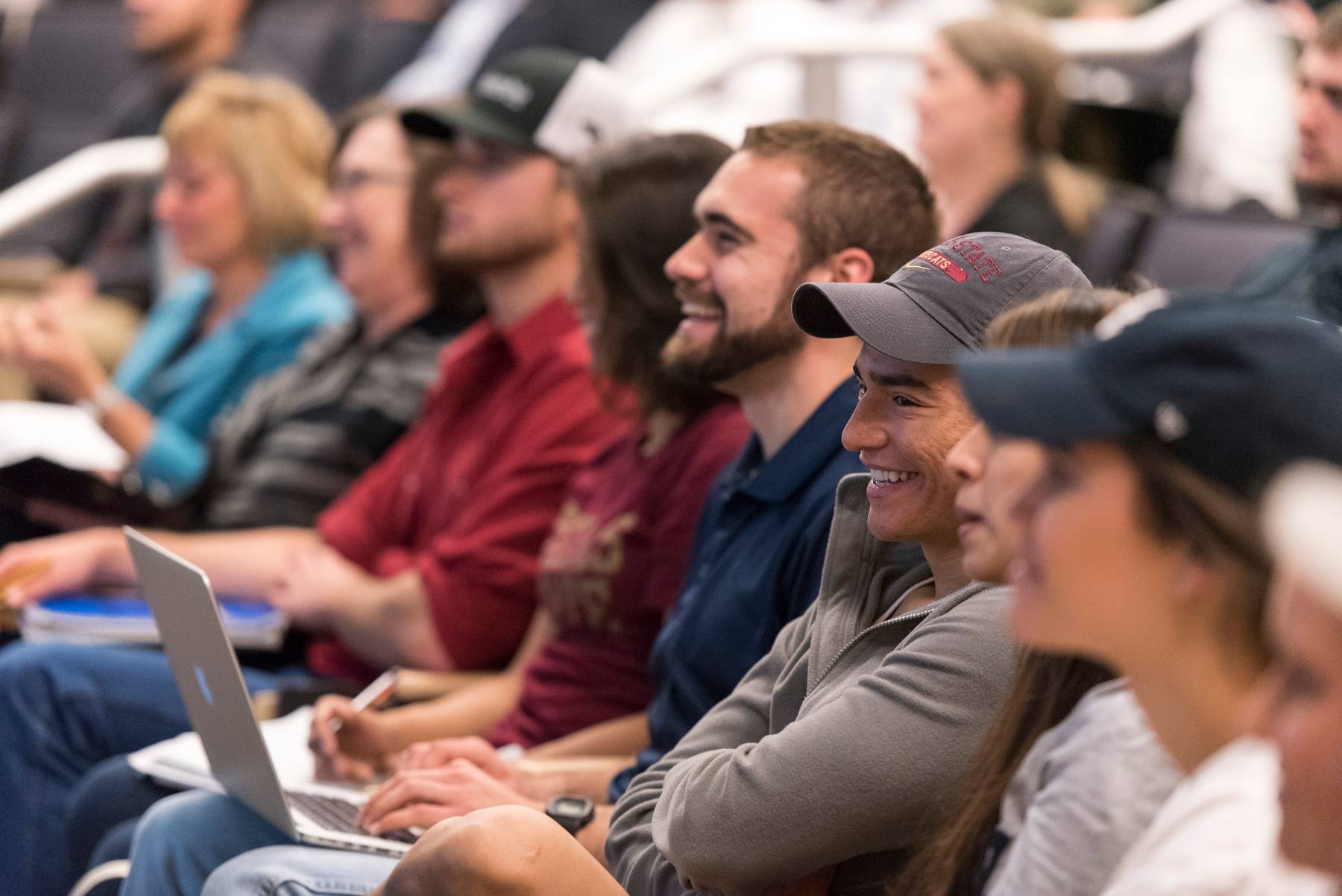 a group of students laugh while sitting in a teaching theatre