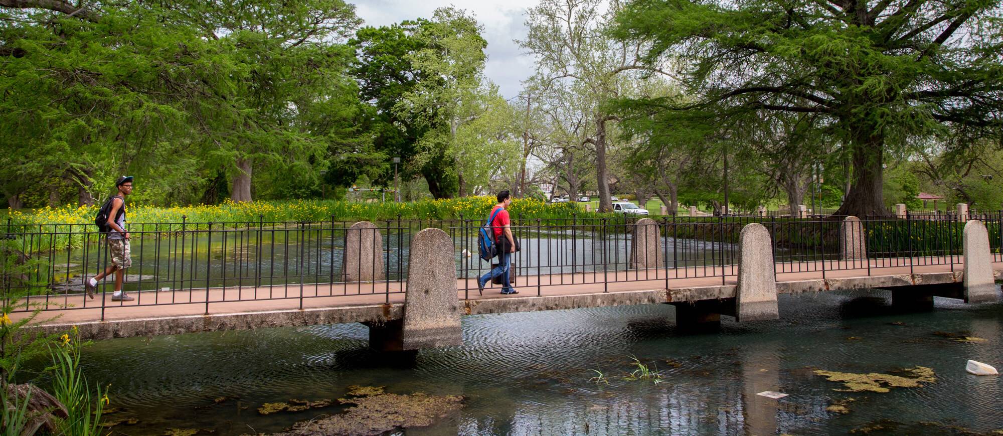 photo of students waling on bridge over a pond