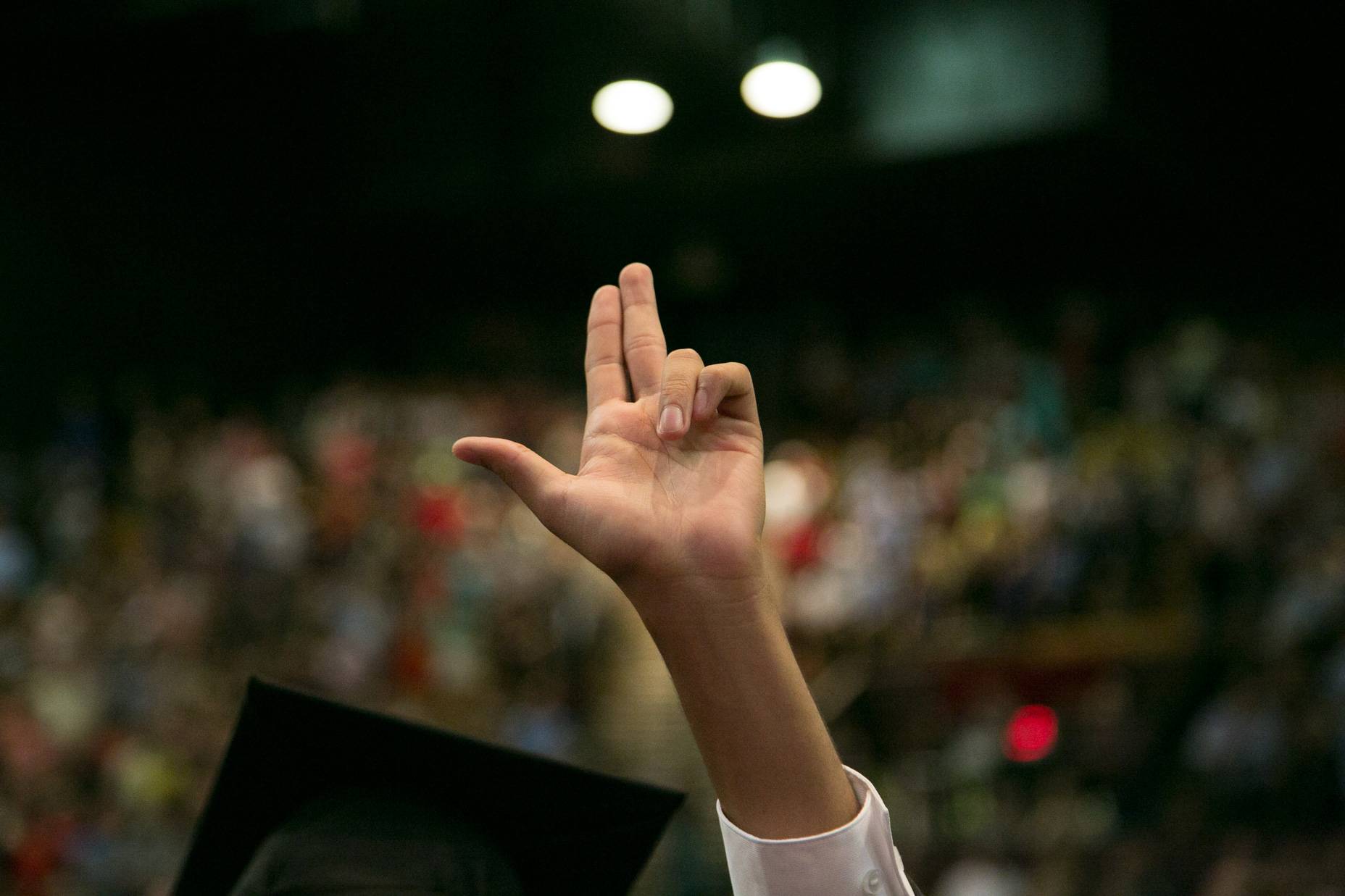 a person at commencement raises their hand in the texas state hand sign