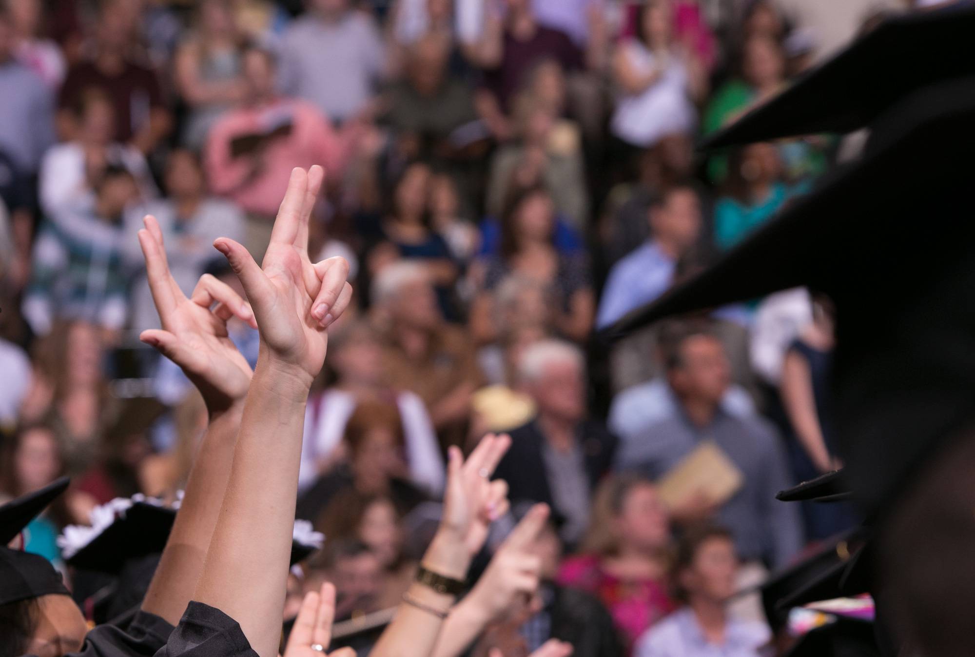 a group of graduates hold up the Texas State hand sign