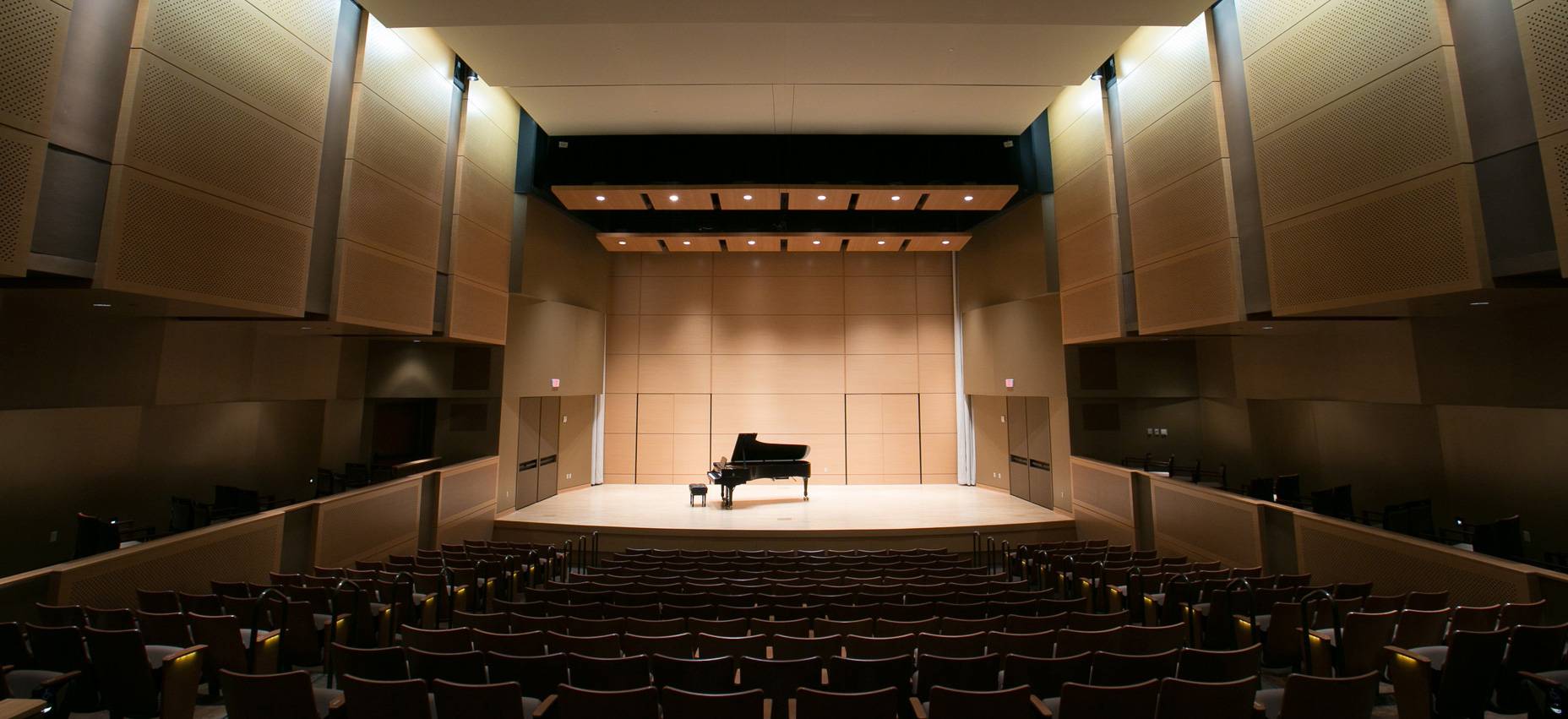 a recital hall with a grand piano in the middle of the picture