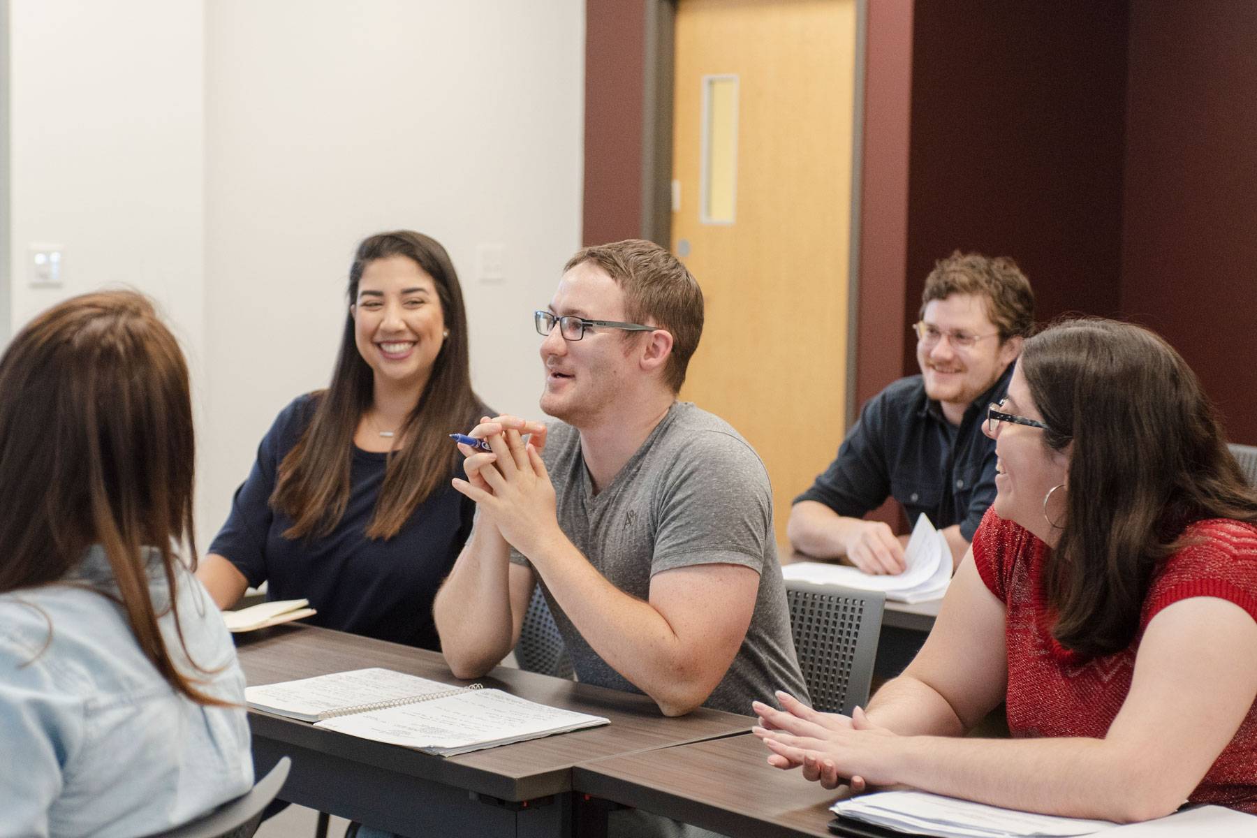 a row of students in a classroom listen to the professor speak