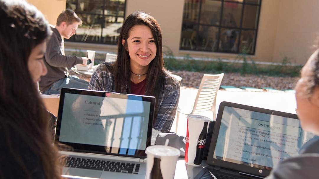 three female students chat while studying at a table outside of Jones Dining Hall