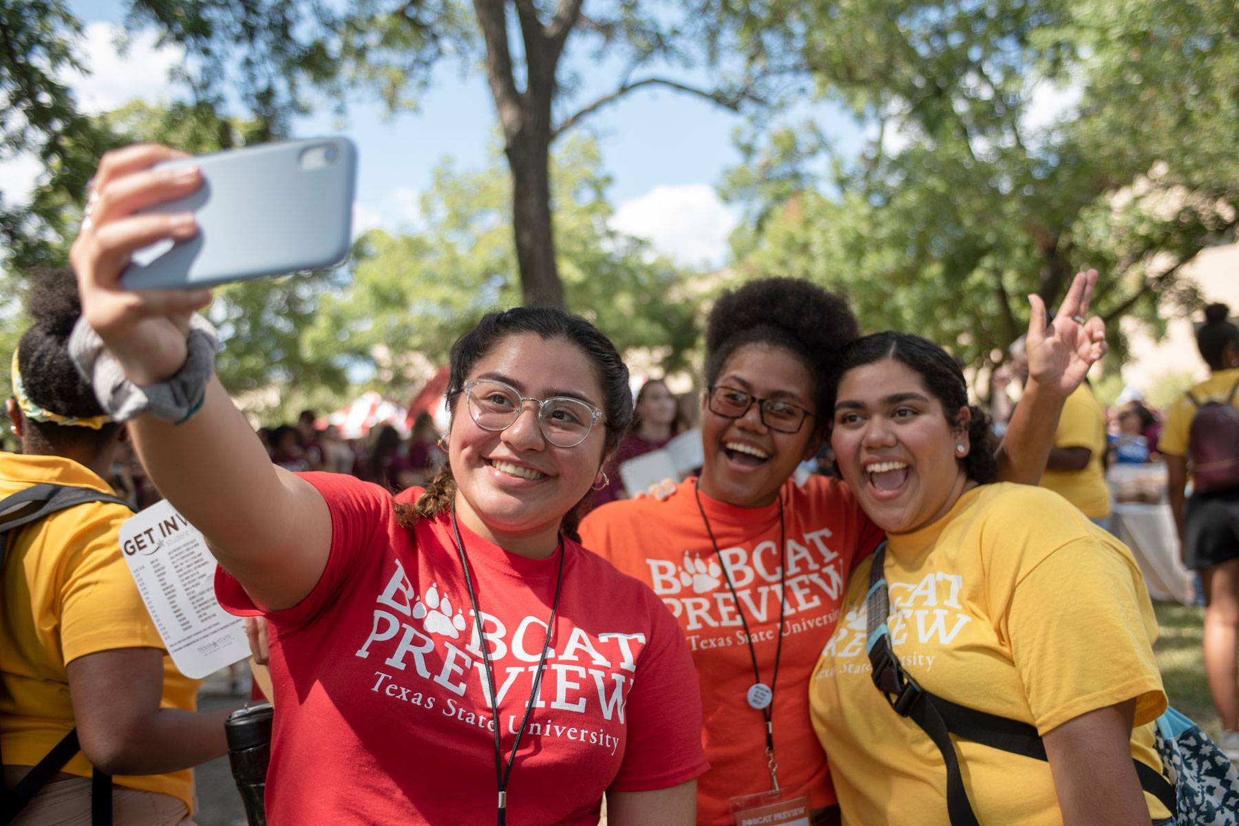 two female students laugh while wearing their texas state apparel