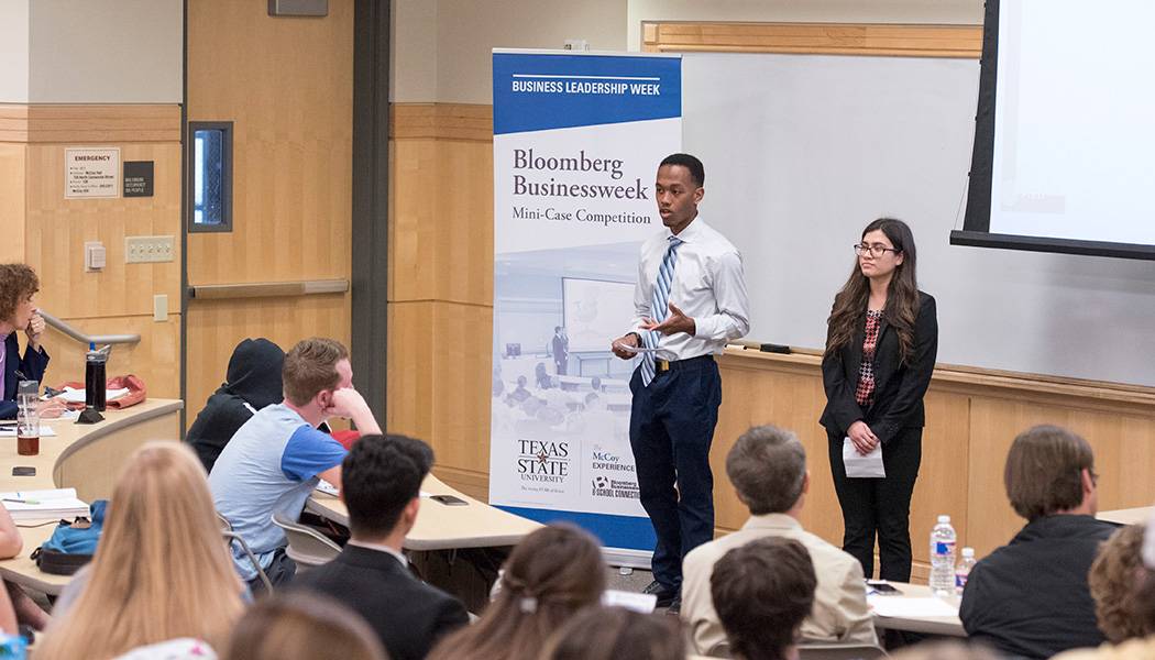 a male and female student give a class presentation during bloomberg business week