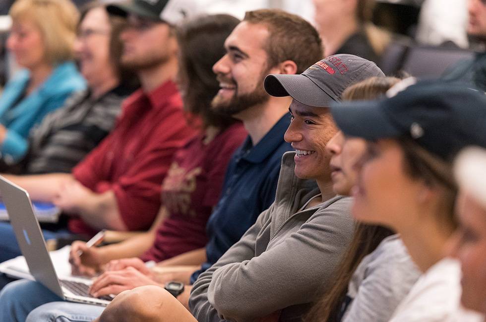 a row of students laugh at a joke told during a lecture