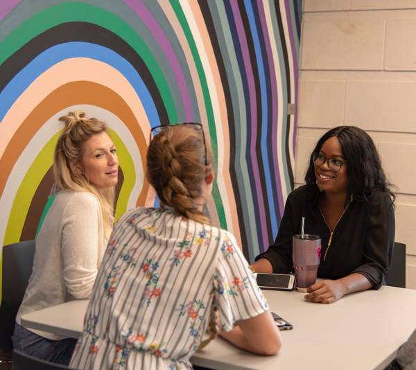 students sitting next to round rock campus mural