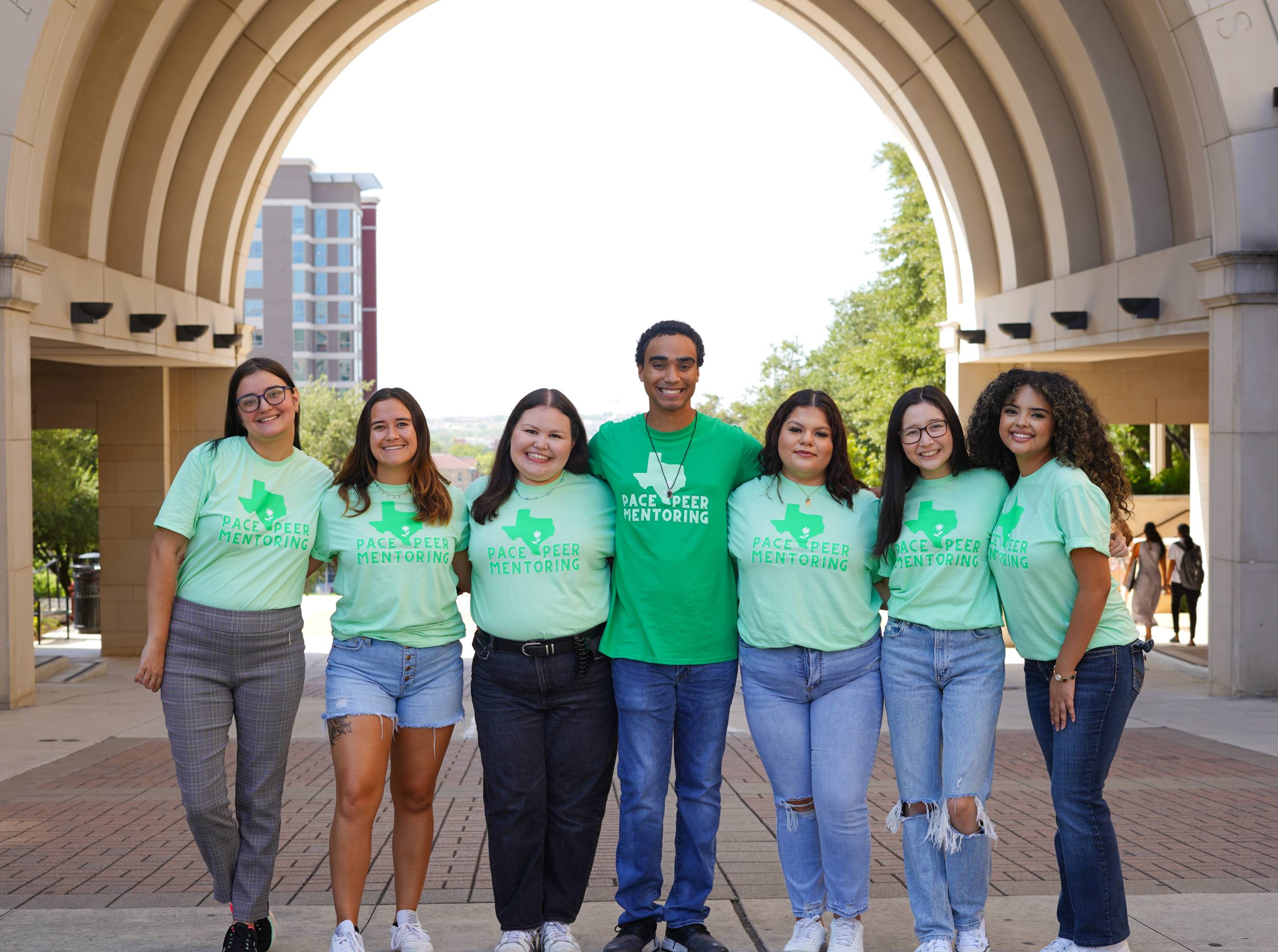 A group of Peer Mentors celebrating in front of the UAC arch.