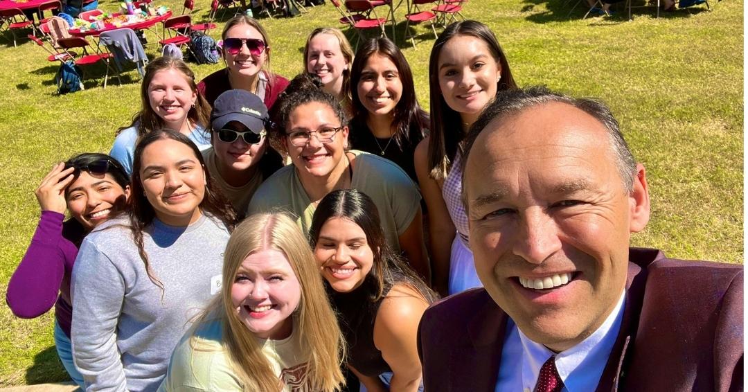 President Damphousse talking a selfie with students