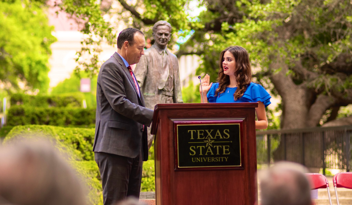 President Damphousse at a podium with female student