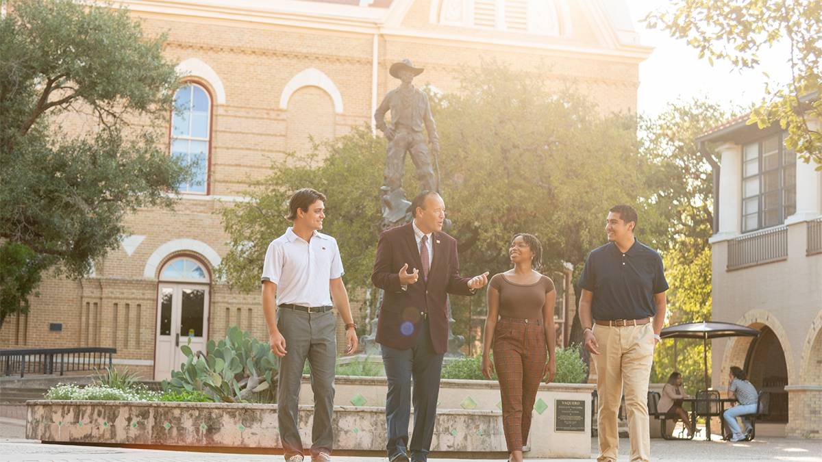 President Damphousse converses with a group of students in front of the TXST Vaquero statue.