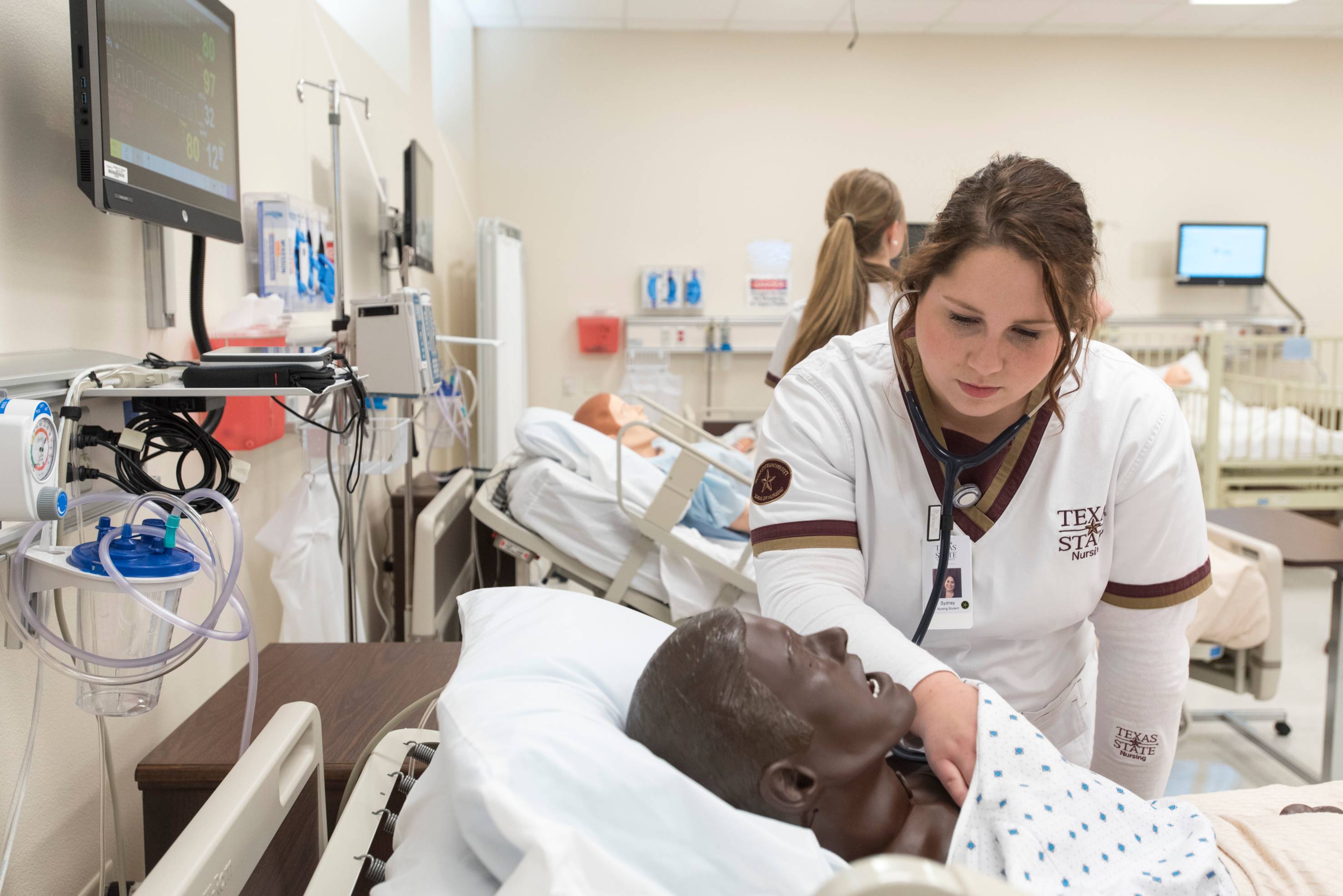 nursing student practices checking vitals on a mannequin