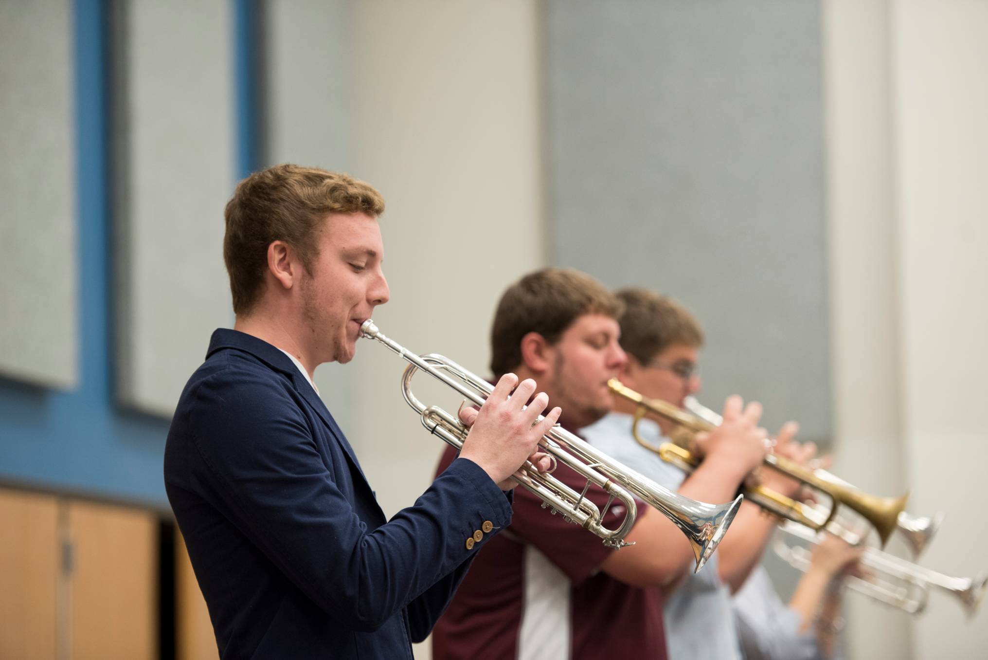 four students in a line playing the trumpet