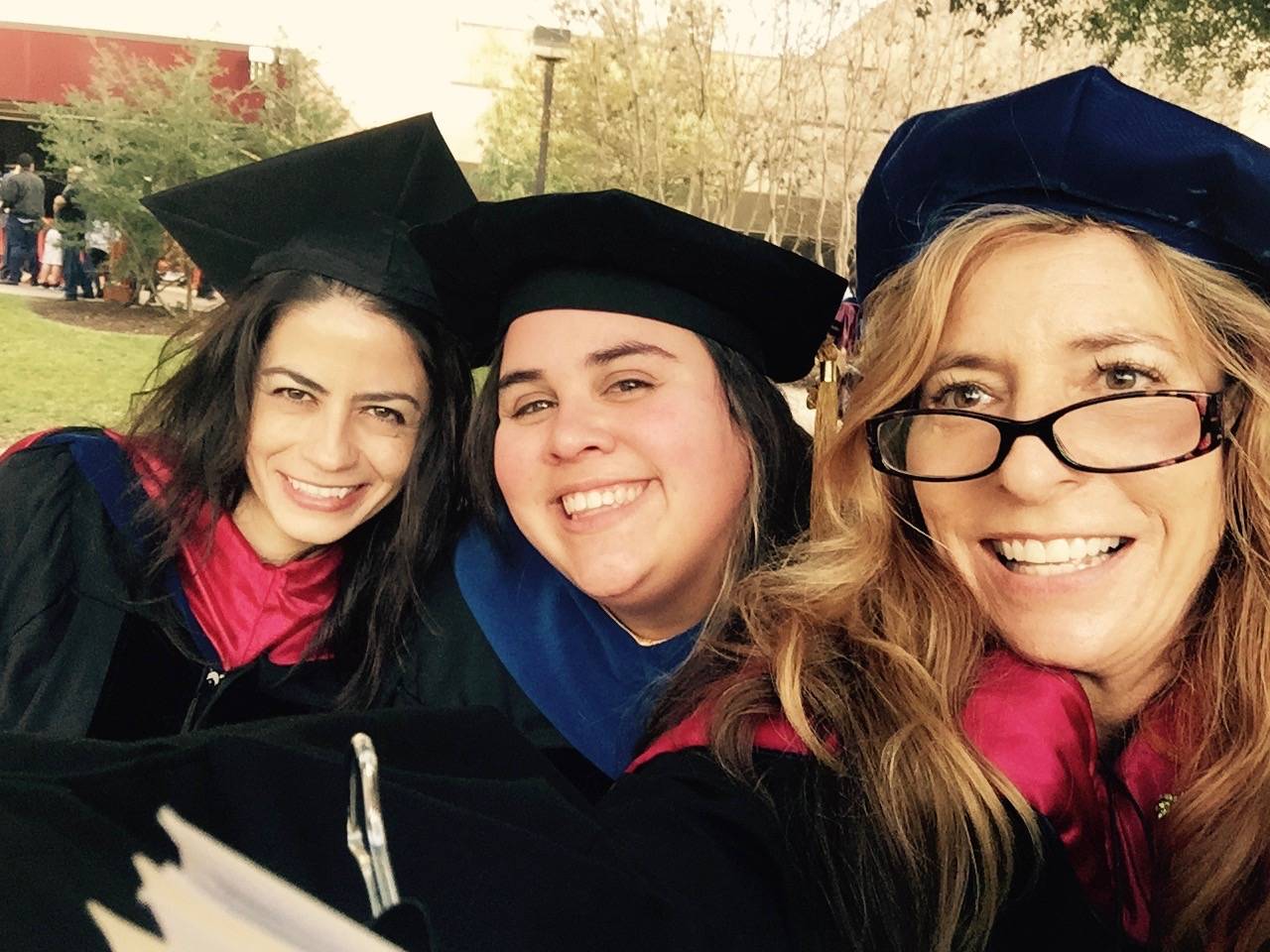 professor and two students in graduation regalia