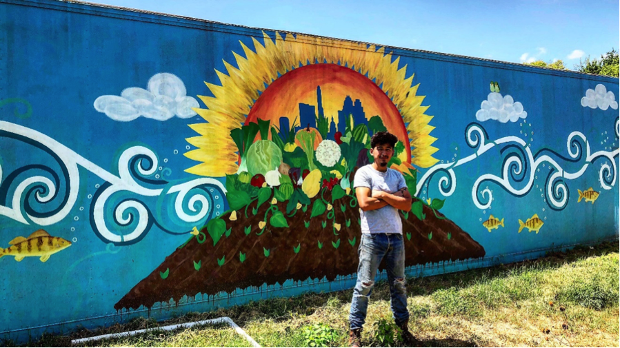 student standing in front of mural of crops and sun