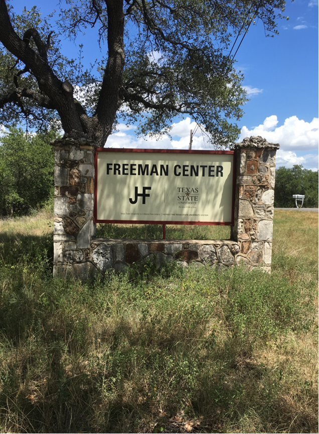 Stone sign under an oak tree that says "freeman center"
