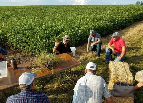 farmers in a field listening to an expert present