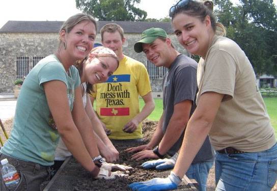Students screening compost, smiling